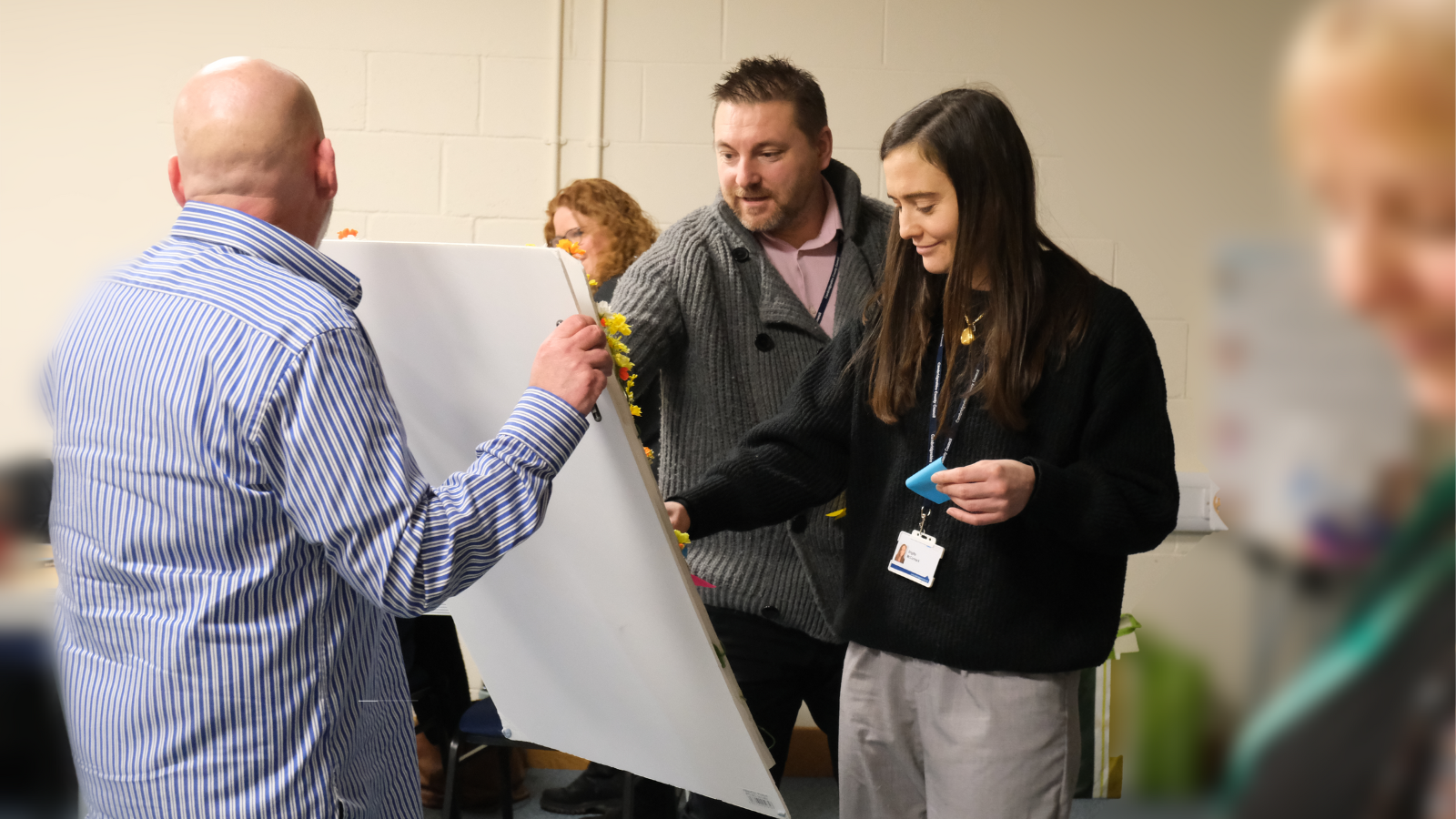 Photo of two people interacting with a ladder poster being held by a facilitator of training