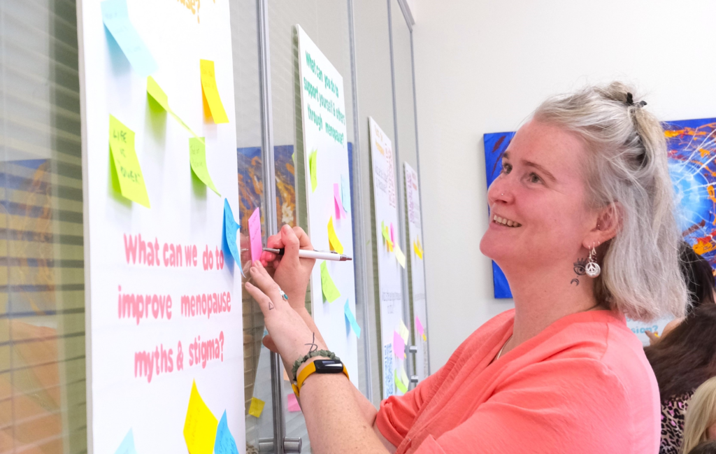 Rachel adding postit notes to a menopause poster